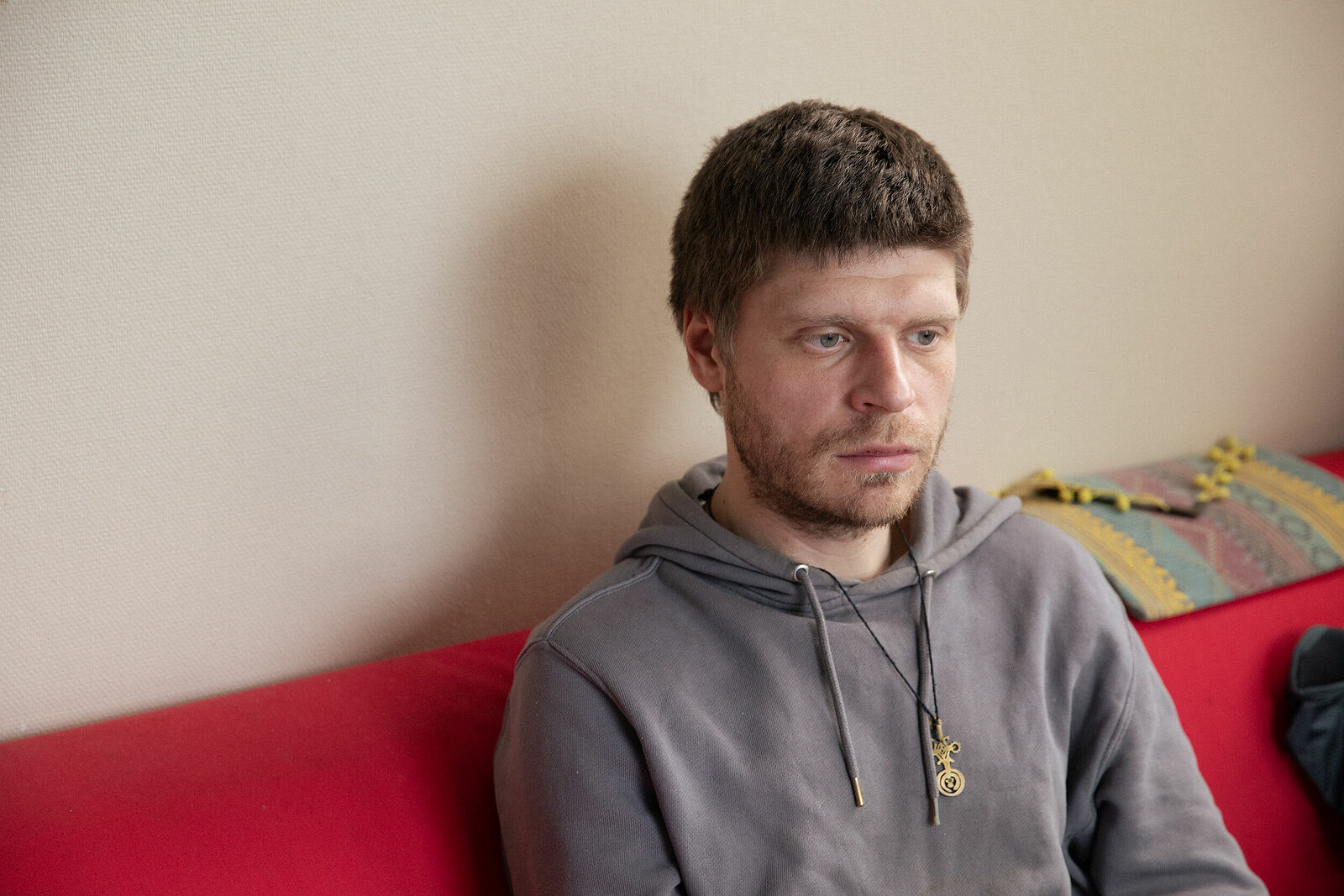 Vasily sitting in the sofa in his room he has in squat in one of the office buildings in Noisy-le-Grand. March 2025.