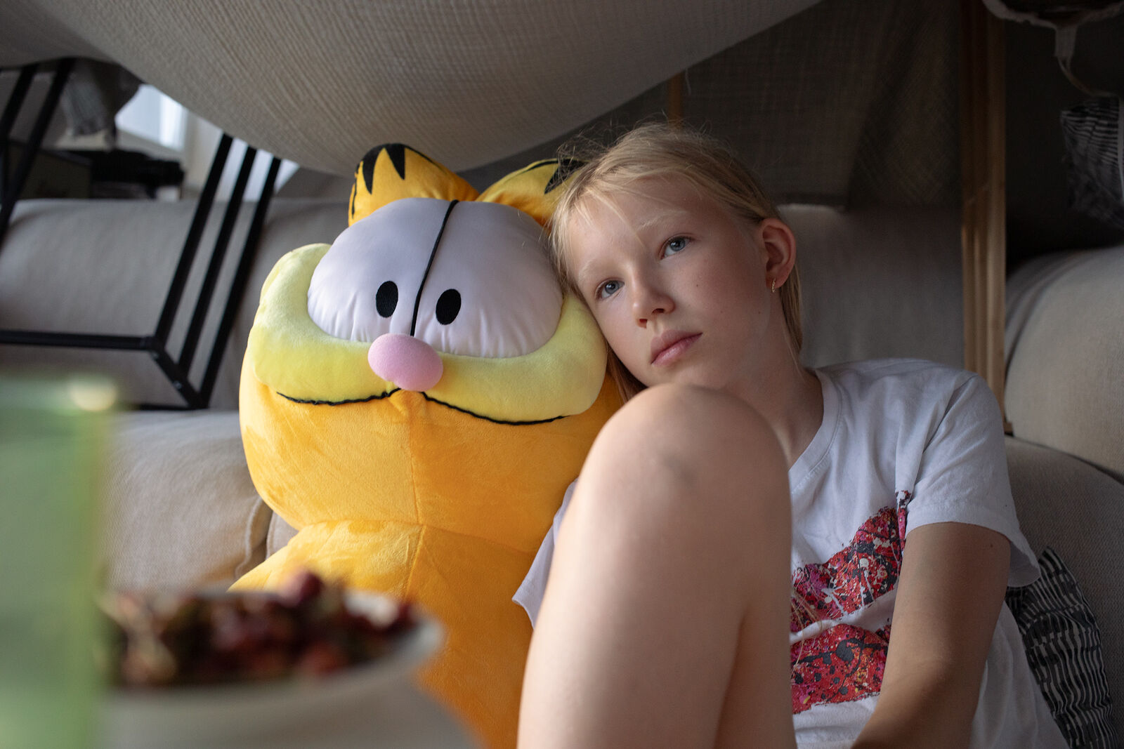 Masha watching a movie in a self-made castle with her toy Garfield. July 2025. Düsseldorf, Germany.